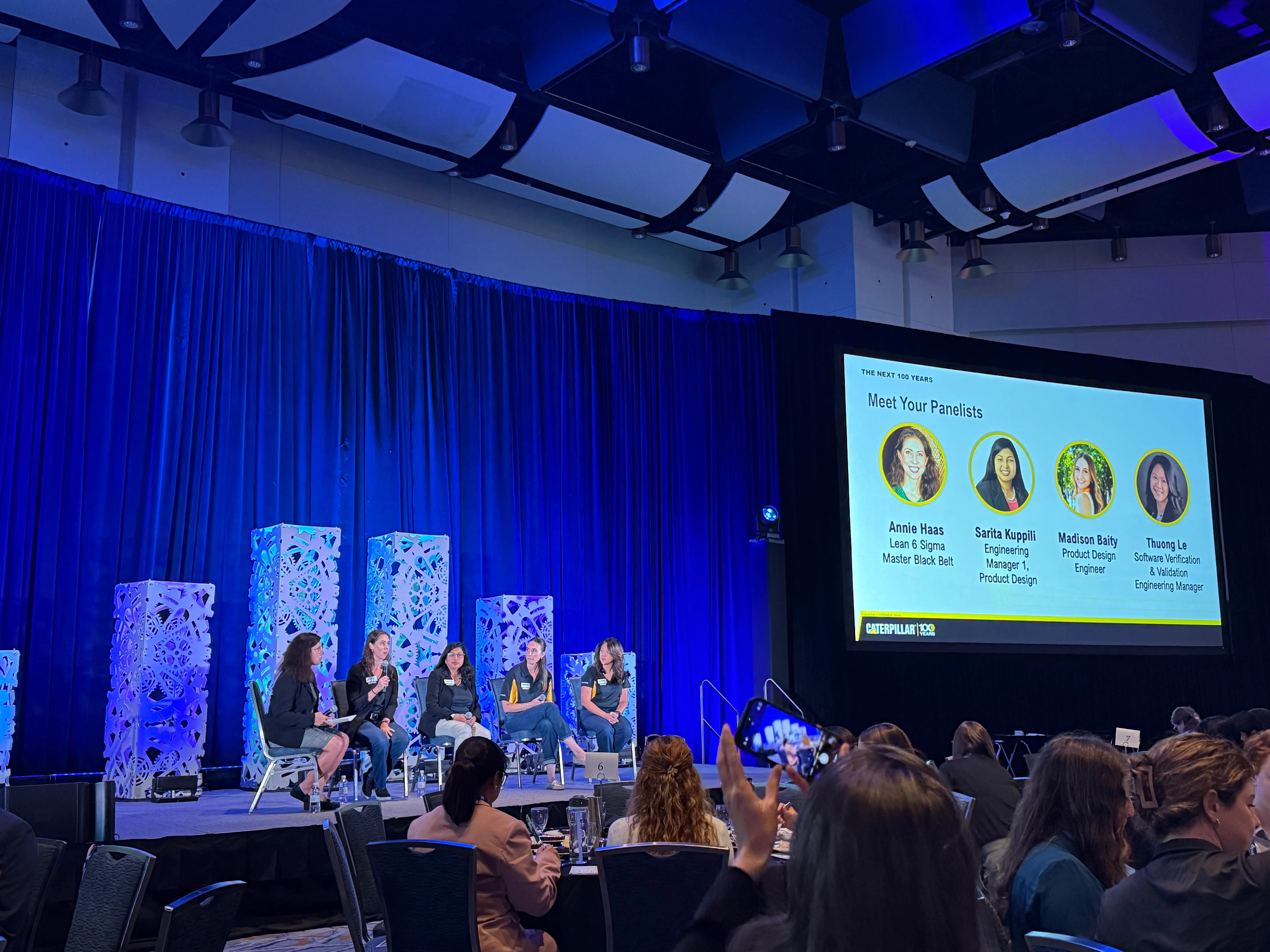 Professional conference panel on a blue-lit stage